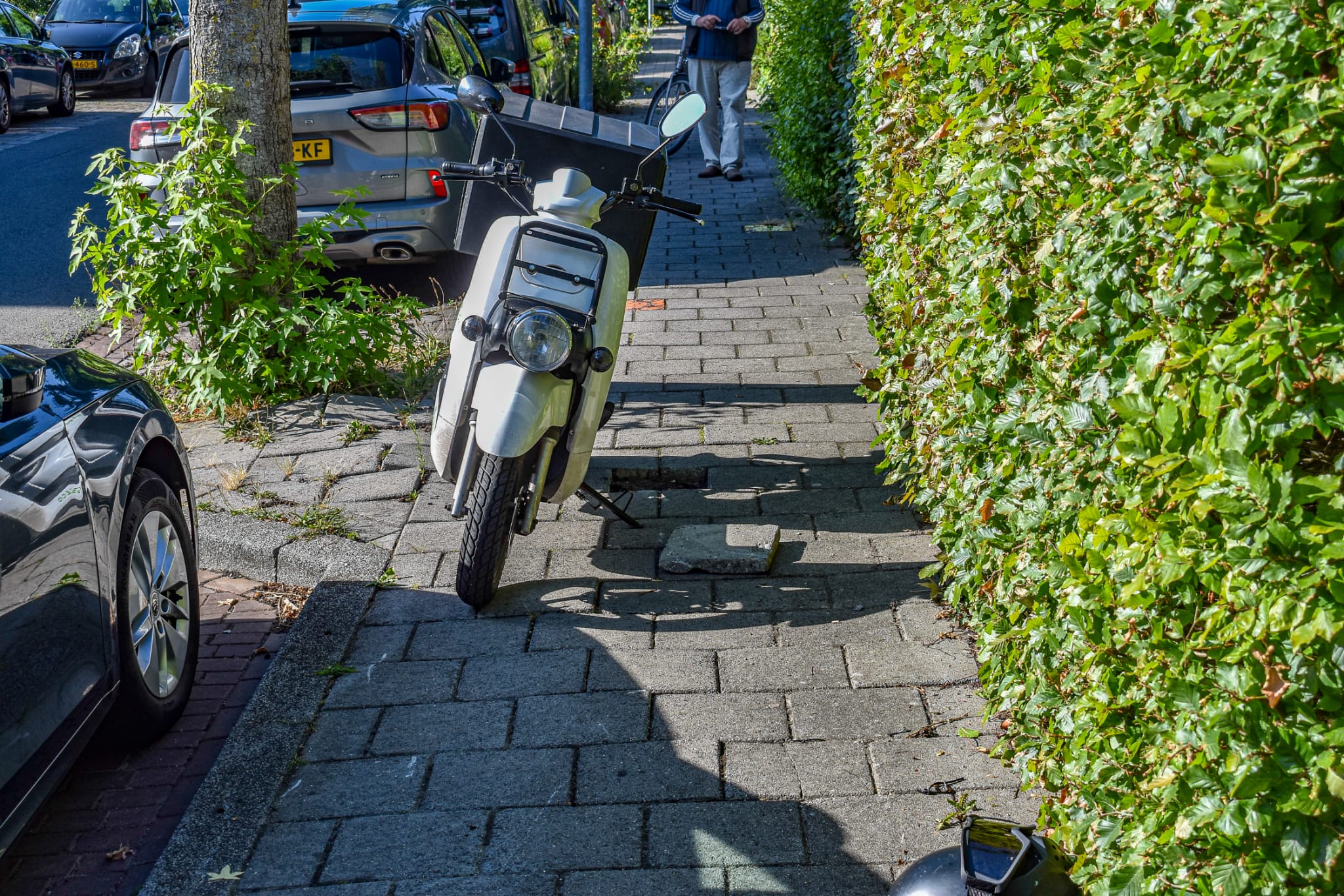 Bezorgscooterrijder botst tegen auto door omhooggedrukte tegel in Voermanstraat